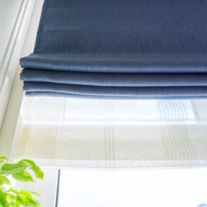 Roman blind in the interior detail close-up Roman blind in the interior detail close-up. Curtain blue blackout fabric, sheers white linen, fashionable modern window decoration design at home